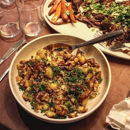 A bowl of MisoHeat smashed potatoes with green garnish