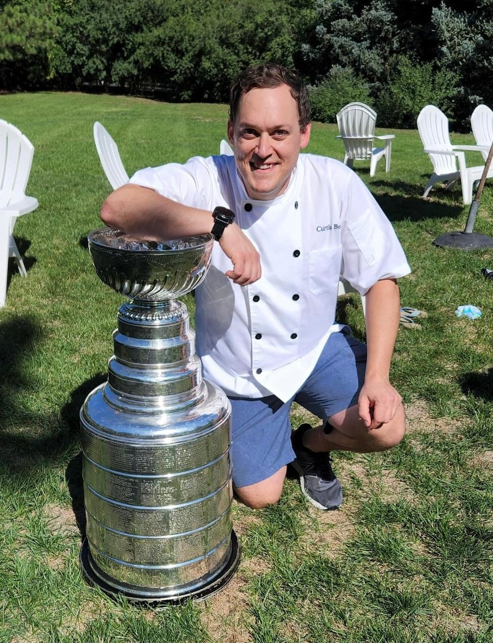 Chef Curtis Bell in his chef coat poses with the NHL Stanley Cup