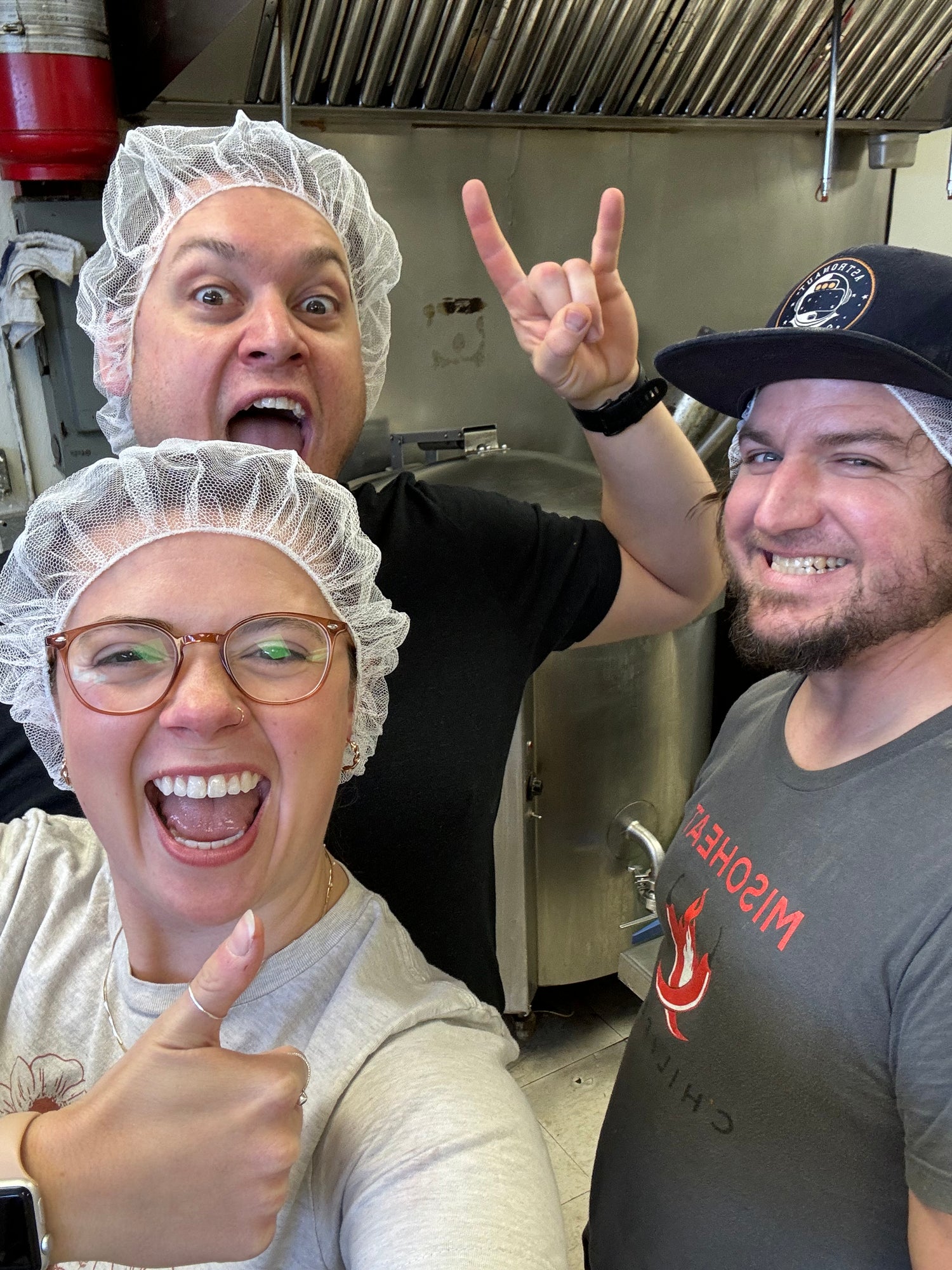 Curtis Bell, Kristen Krak, and Alan Hope sport hairnets in the MisoHeat production kitchen